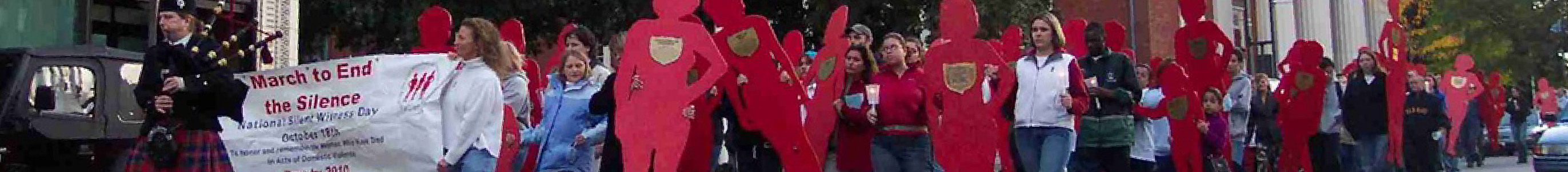 banner image: Silent Witness March. People Marching with red shilohet cardboard cutouts